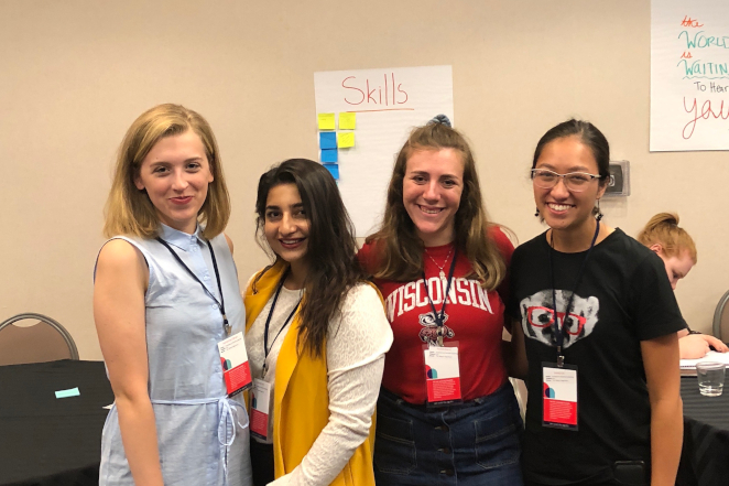 Students smiling at the camera and wearing conference lanyards and UW-Madison gear.