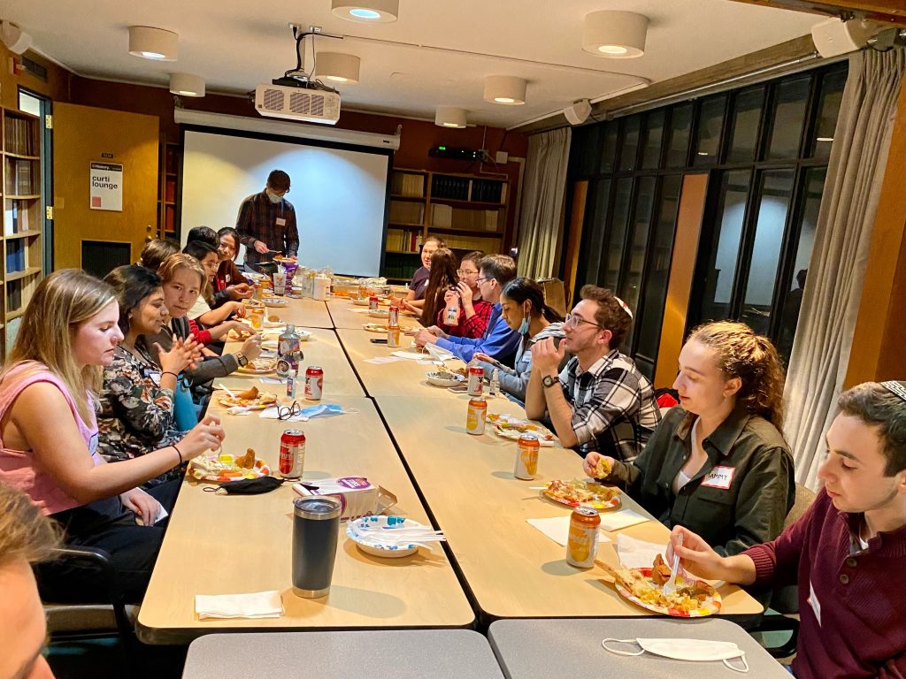 Students sitting around a long table and eating a meal together.